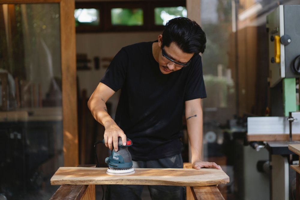 Sanding a wood surface back to bare timber.